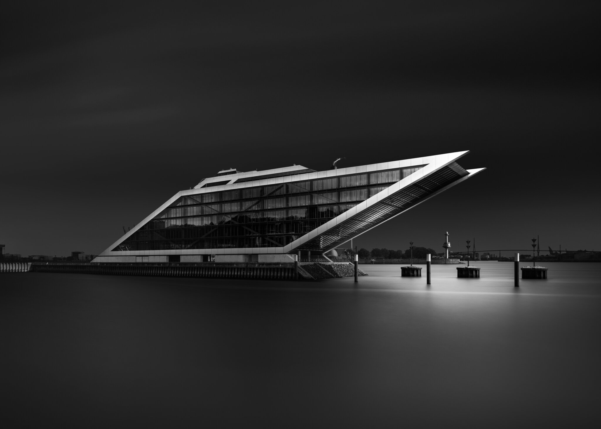 Long exposure black and white fine art photograph of an angular floating architectural structure on a still waterfront in hamburg