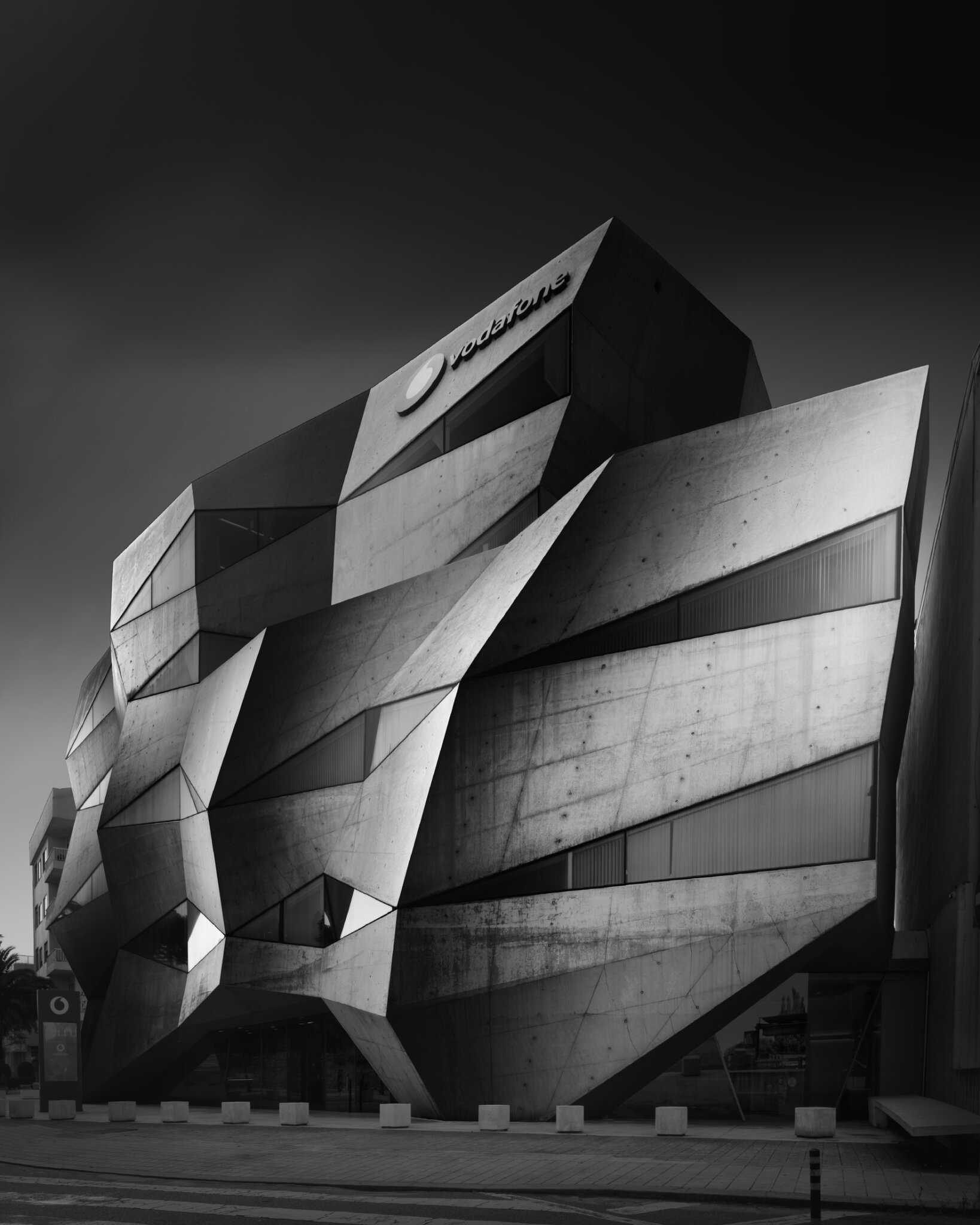 Black and white fine art photograph of a contemporary building with sharply angular folded metal facade panels