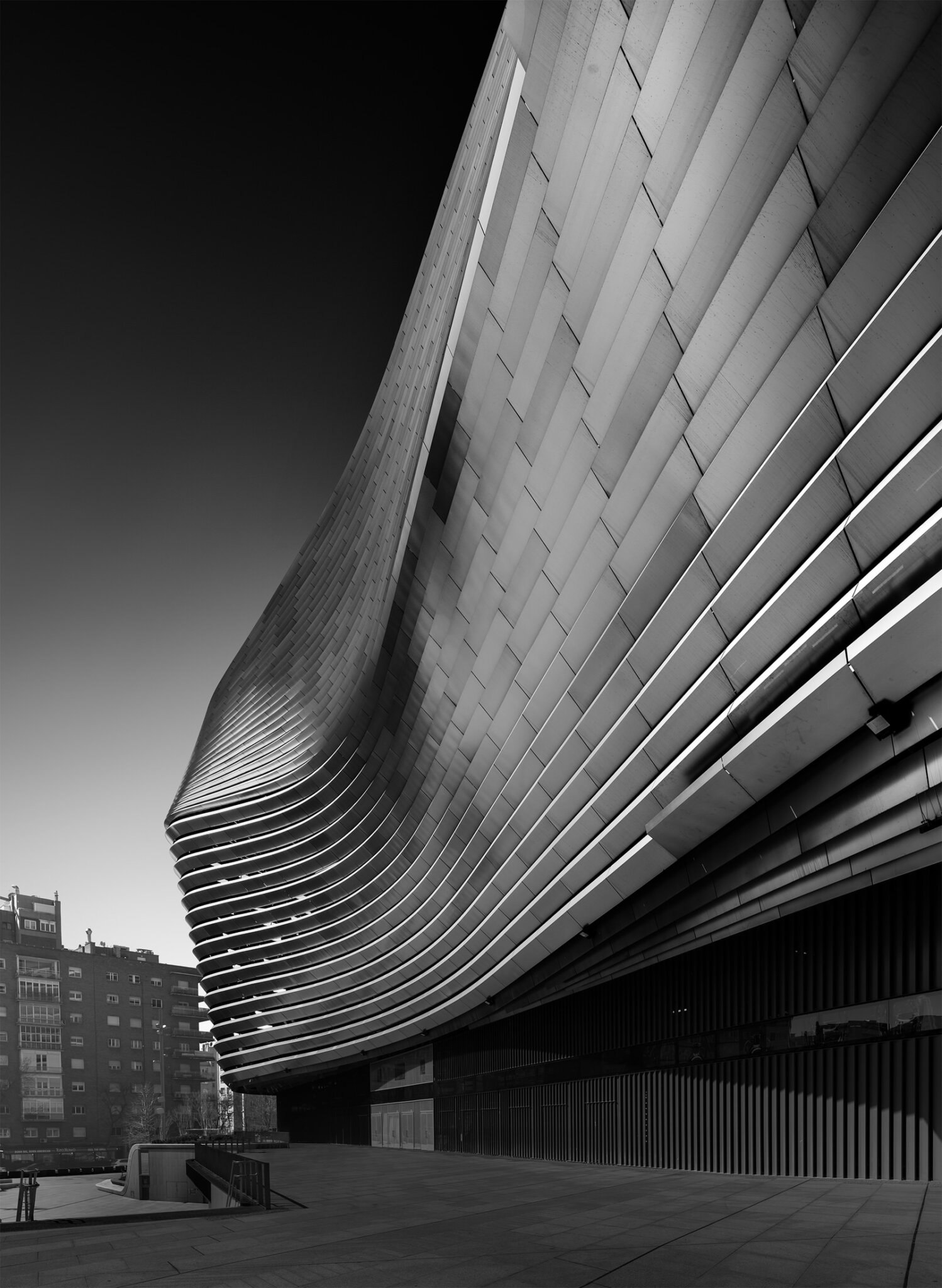 lack and white fine art close-up of the sweeping curved metal facade of the bernabeu stadium in madrid with dramatic ribbed surface details