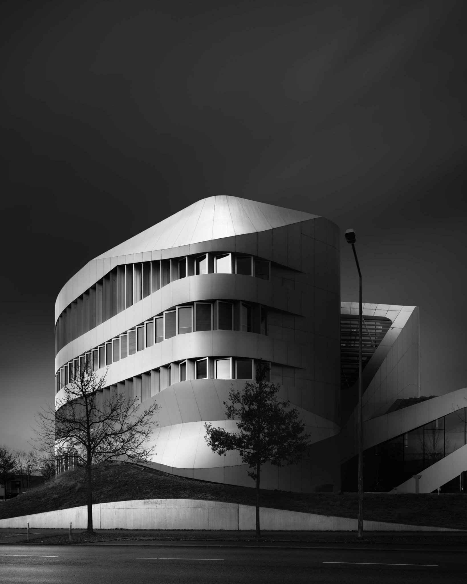 Black and white fine art photograph of a circular modernist building with sweeping horizontal bands
