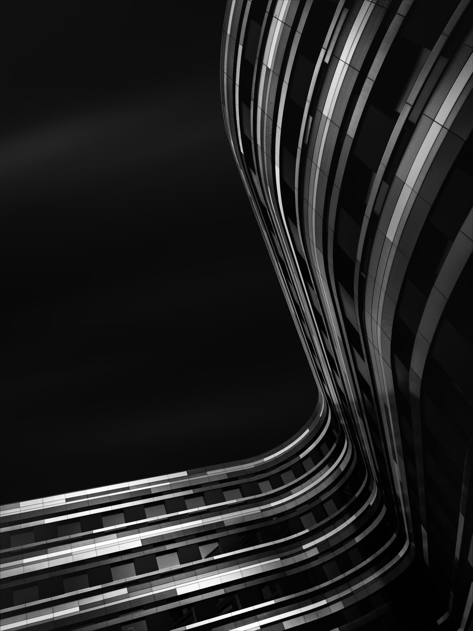 Abstract black and white fine art photograph of sweeping curved highway or metro infrastructure with dynamic light trails