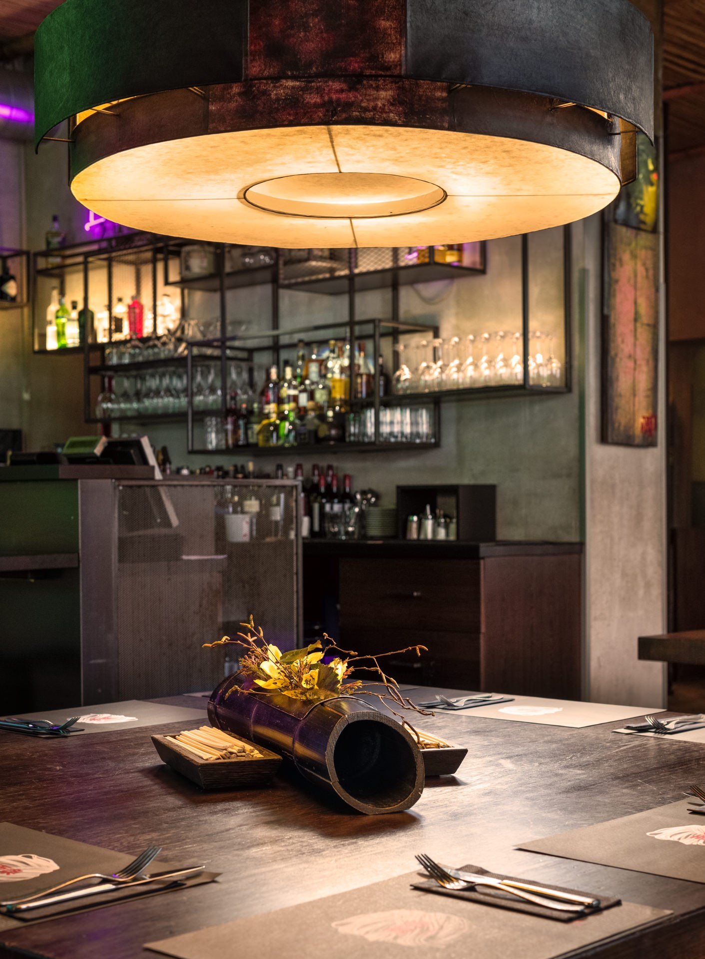 Eclectic restaurant interior with industrial pendant lighting, vintage furniture, and a glowing neon sign