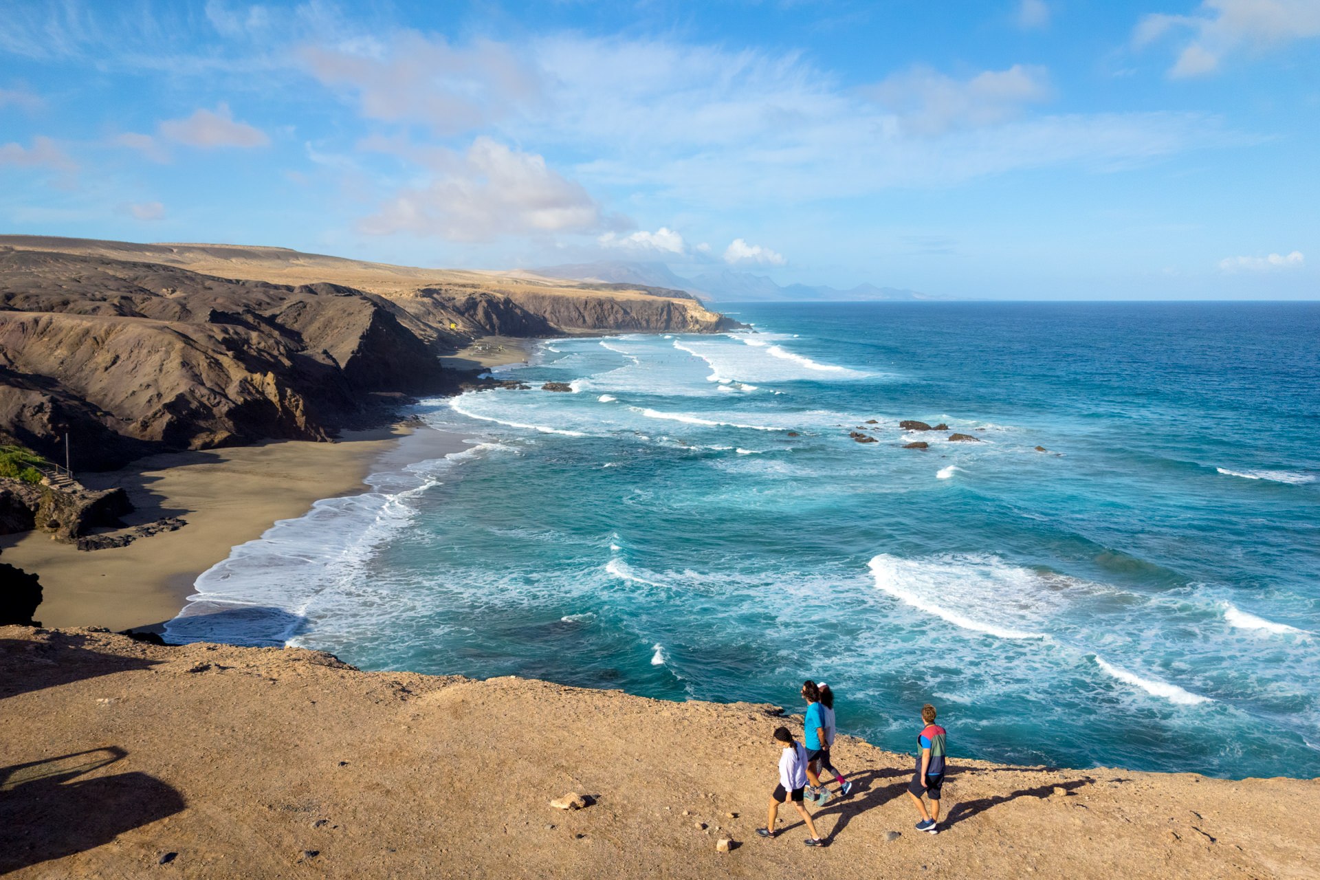 Dramatic Atlantic coastal cliffs with turquoise water and a family exploring the rocky shore — destination photography