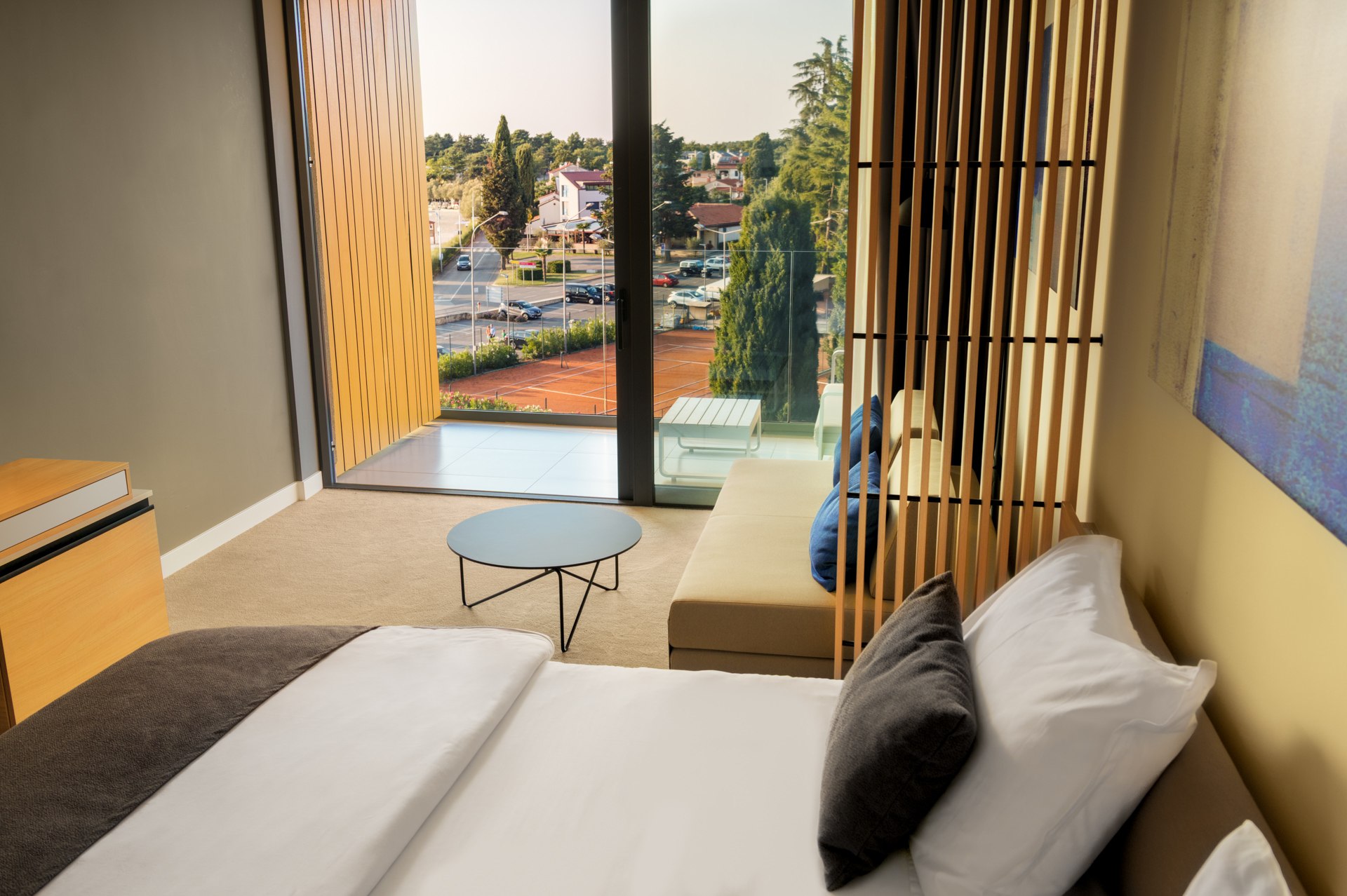 Contemporary hotel double room with large panoramic sea-view window and warm wood slatted wall panel
