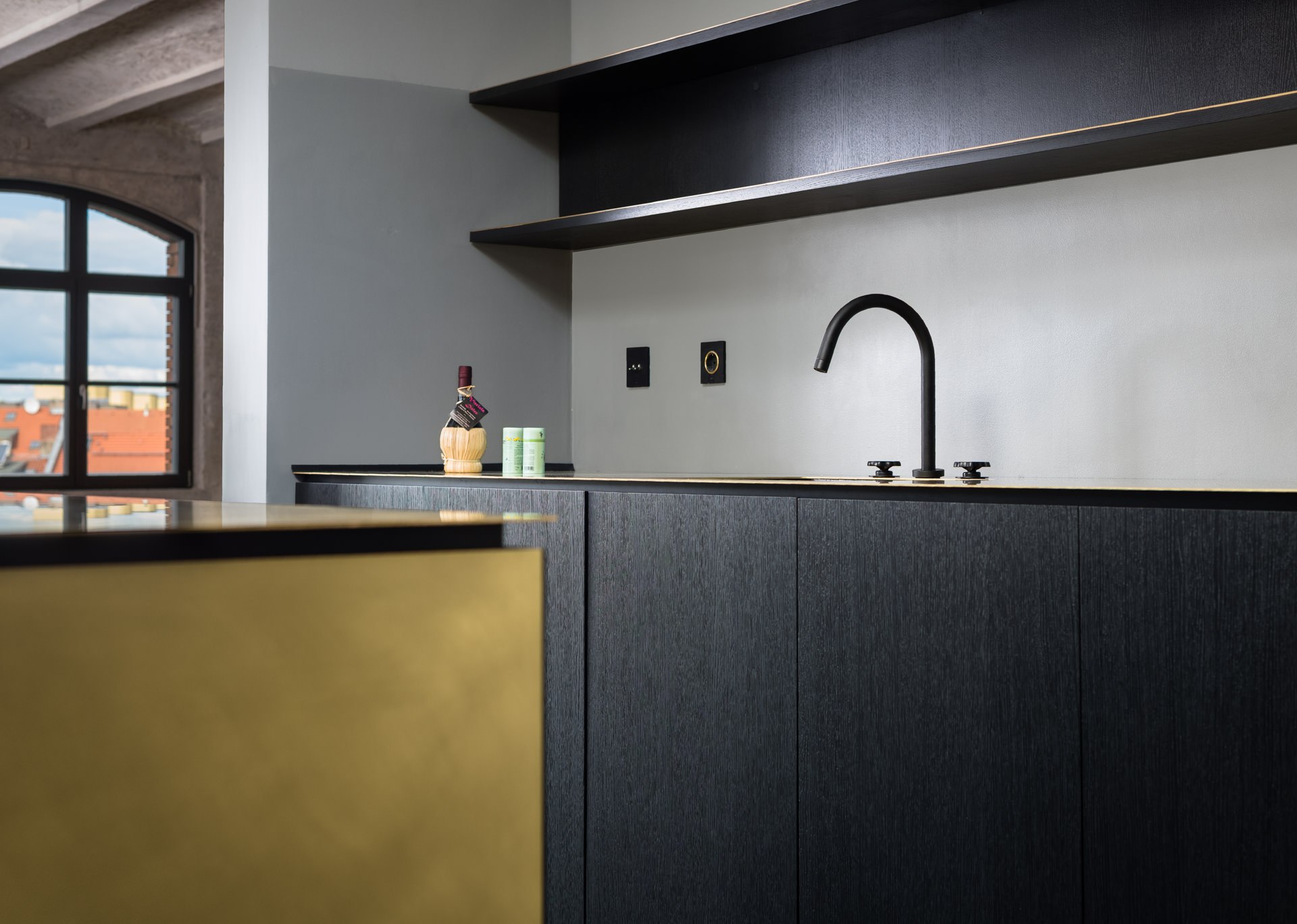 Close-up detail of a custom kitchen island with brushed brass and matte black surfaces — interior design photography