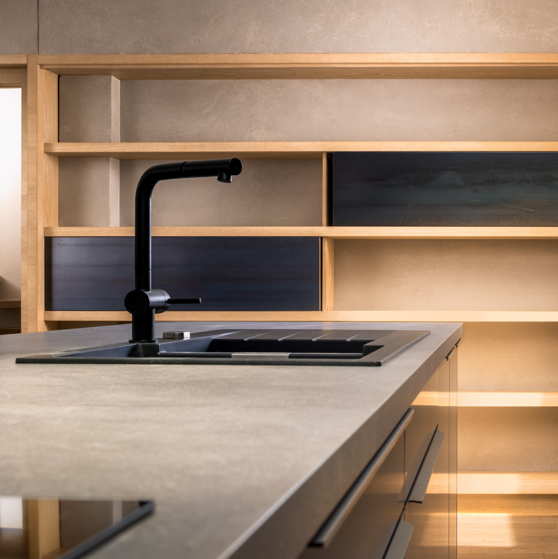 Close-up overhead view of a wooden kitchen island with a matte black tap and custom open shelving