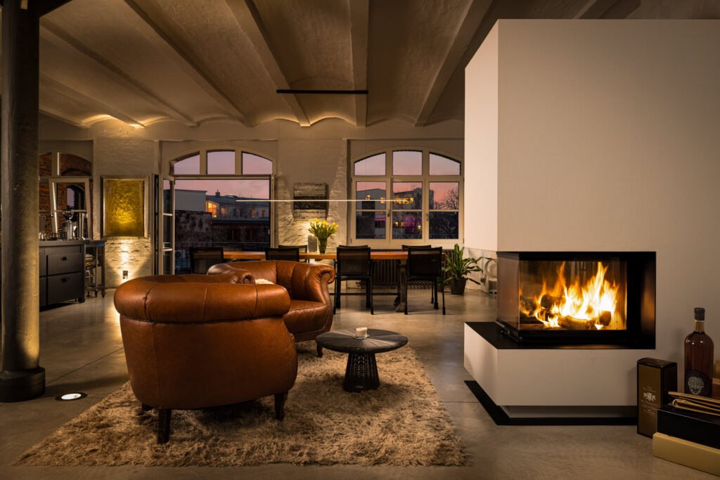 Warm living room with an open fireplace, leather club chairs, and soft evening ambient lighting