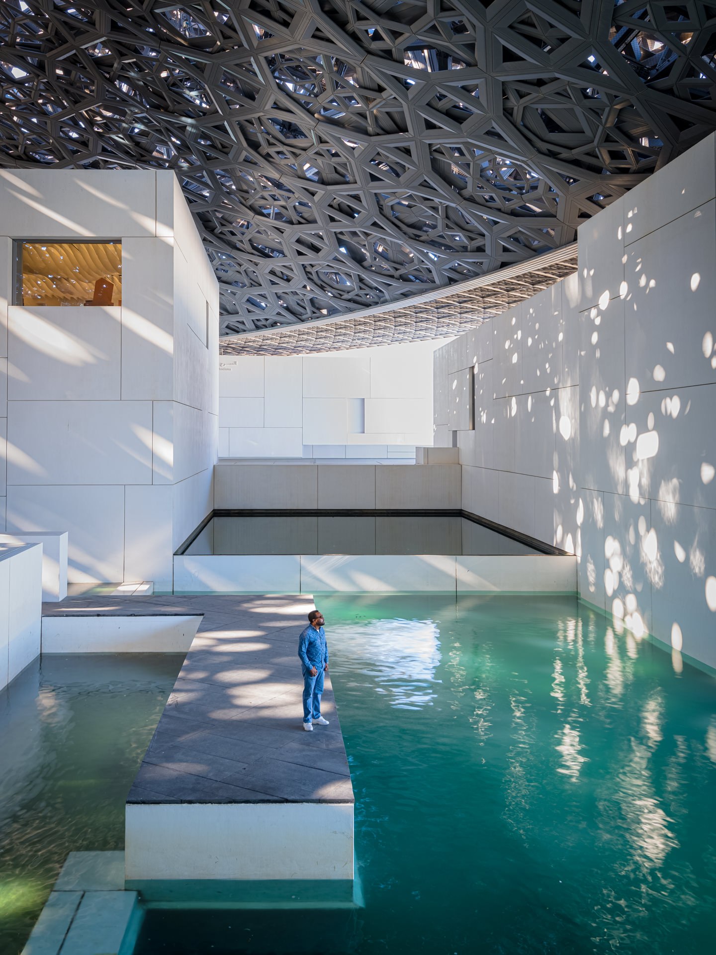 Fine art aerial photograph of the Louvre Abu Dhabi museum with its iconic geometric latticed dome and water reflections