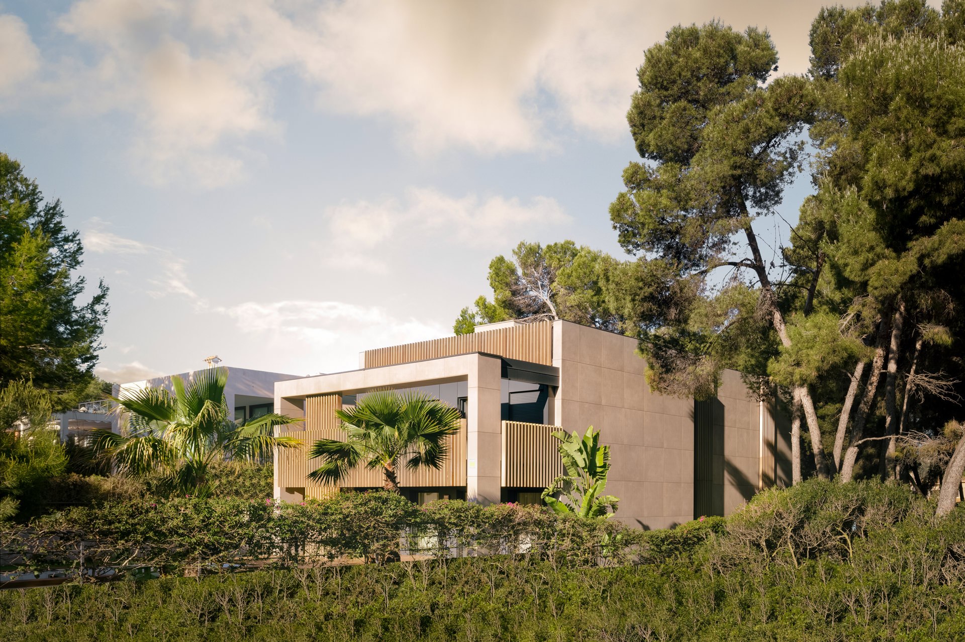 Contemporary Mediterranean villa with stone and concrete exterior nestled in a lush hillside landscape