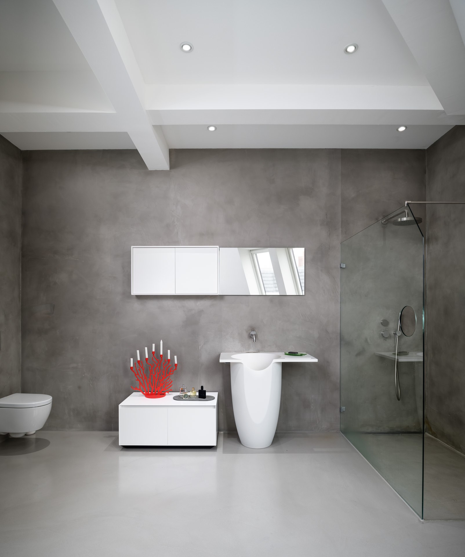 Minimalist bathroom with polished concrete walls, freestanding white fixtures, and a walk-in glass shower