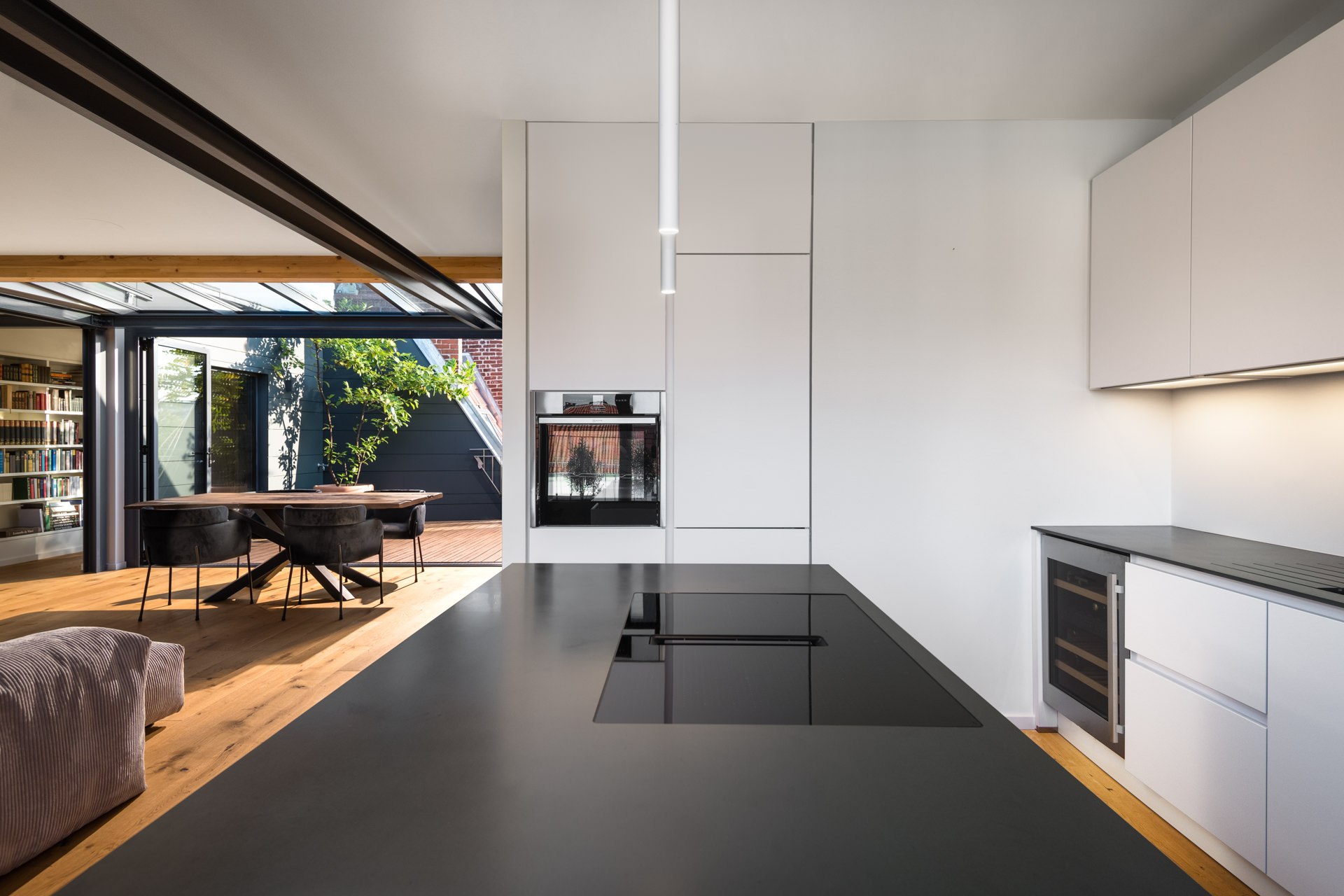 Contemporary kitchen with a long island, glass front facade, and seamless terrace connection — architectural interior photography
