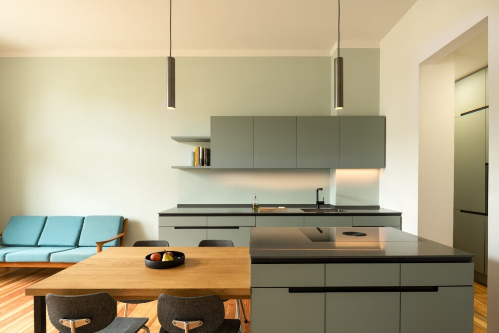 Bright open-plan kitchen and dining area with light timber cabinetry, pendant lighting, and a long central island