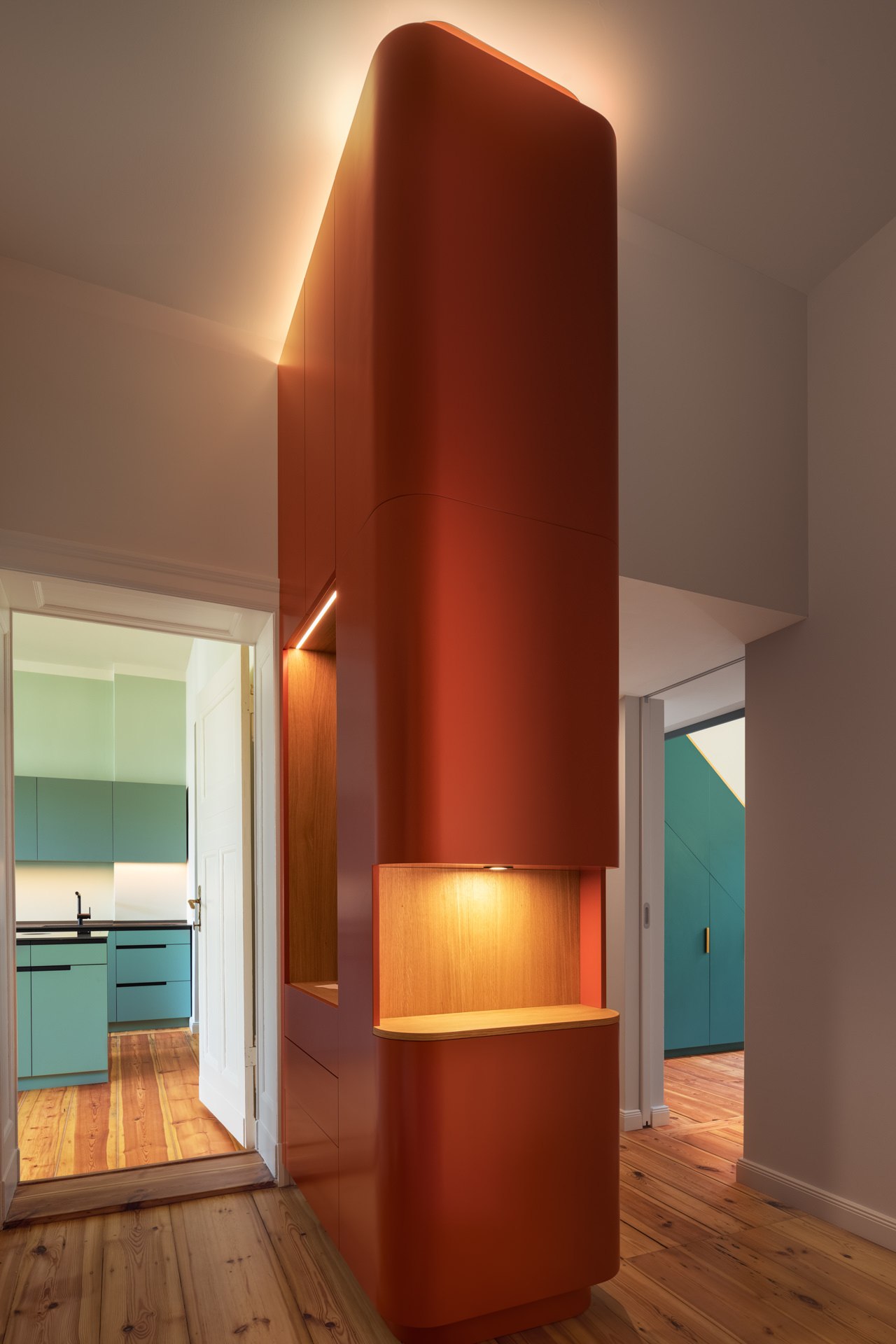Architectural interior corridor featuring a dramatic red cylindrical volume with warm directional lighting