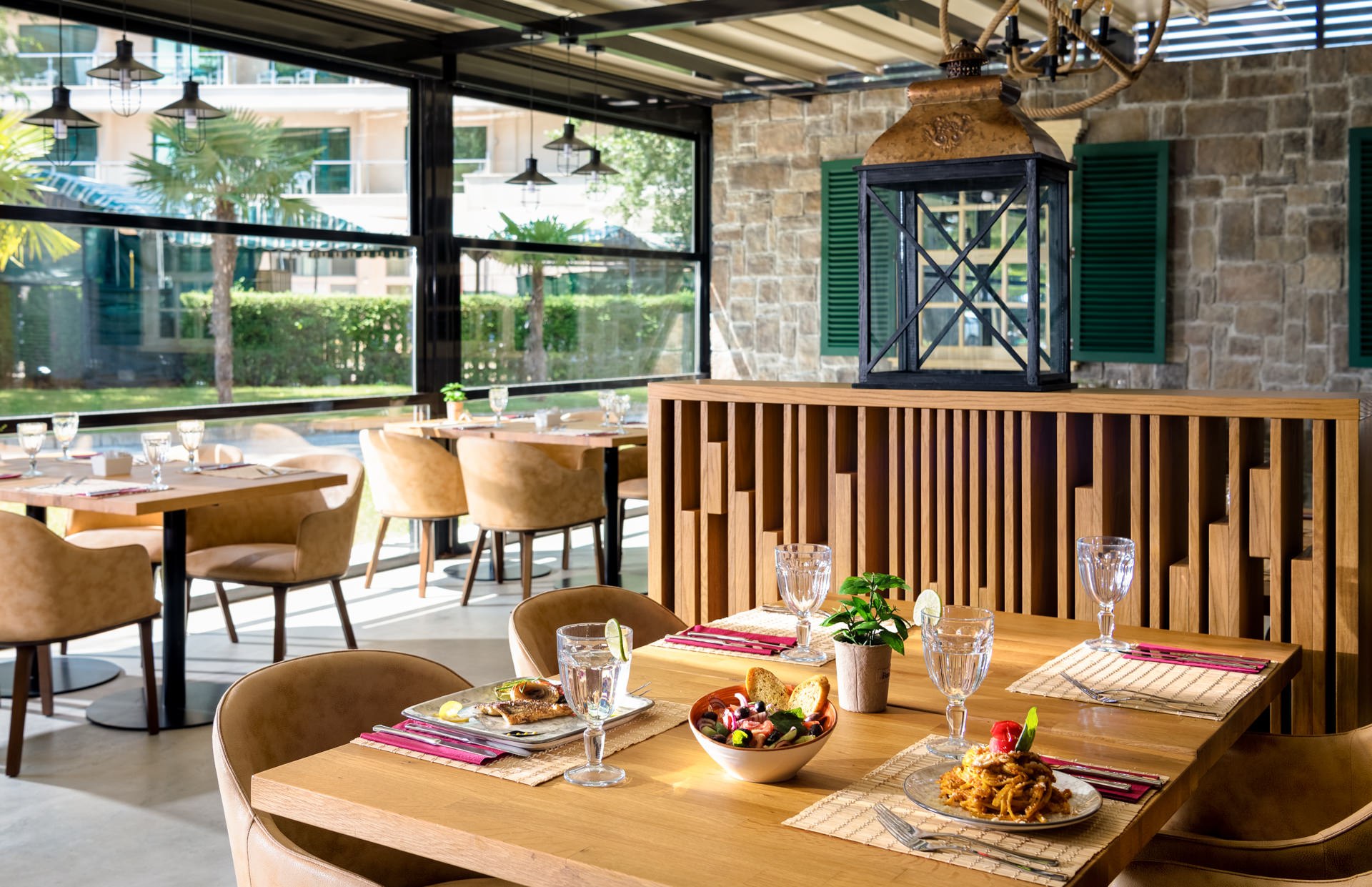 Rustic Italian restaurant interior with stone walls, wooden beams, rattan pendant lights, and set tables