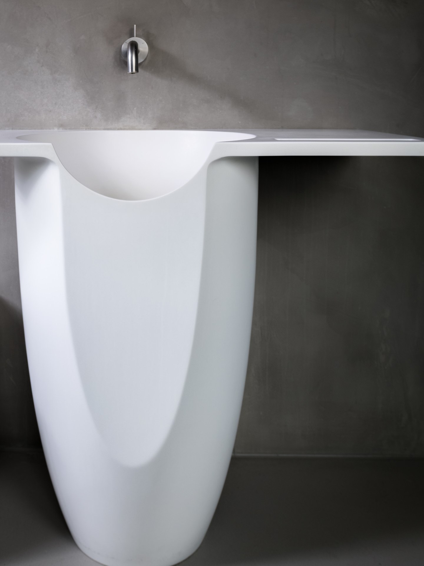 Striking sculptural freestanding bathtub with an elongated silhouette against a dramatic dark background