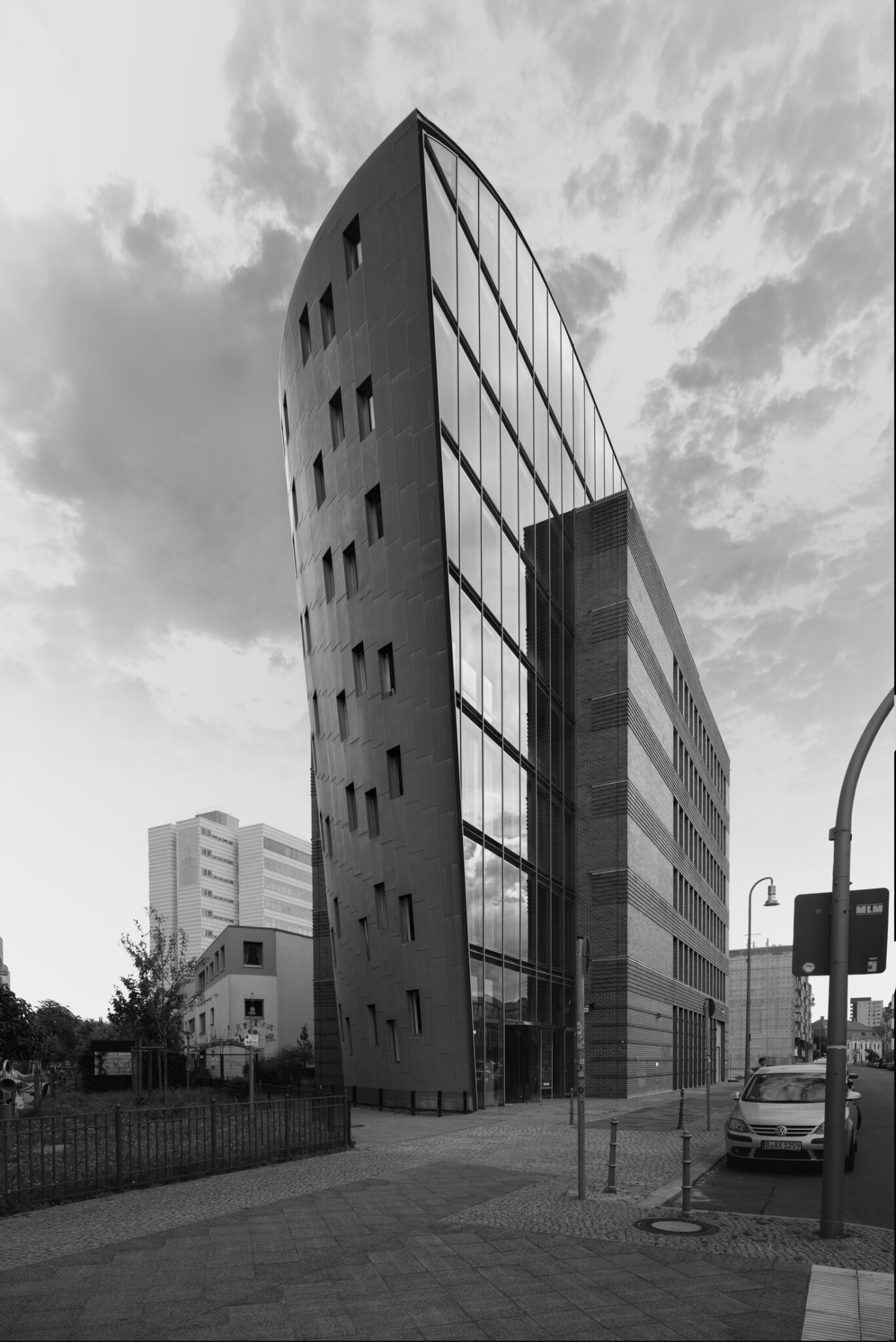 Black and white fine art photograph of a slender tower with alternating glass and stone facade on an urban street