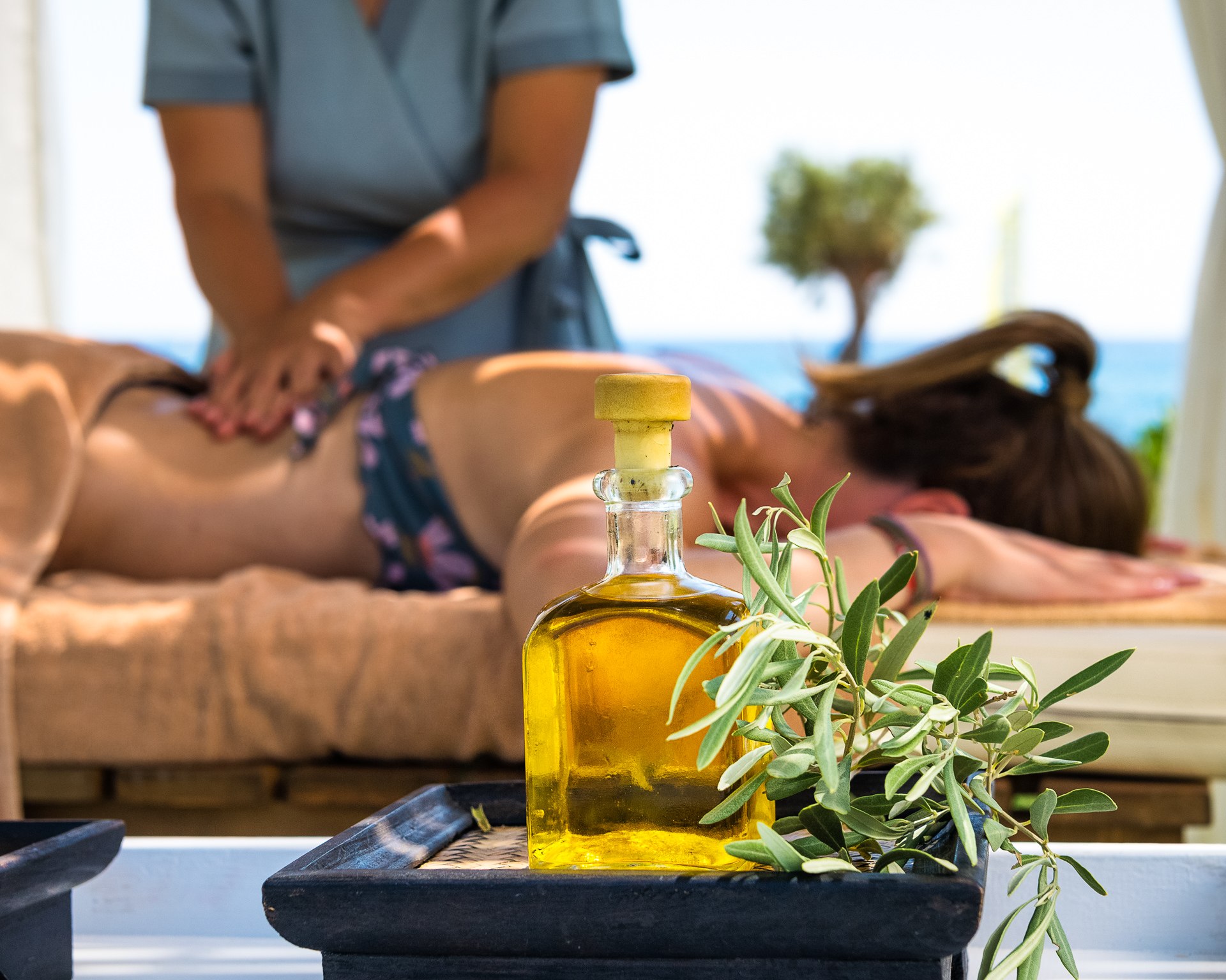 Outdoor spa massage session with aromatic oil and olive branch at a luxury Mediterranean wellness resort
