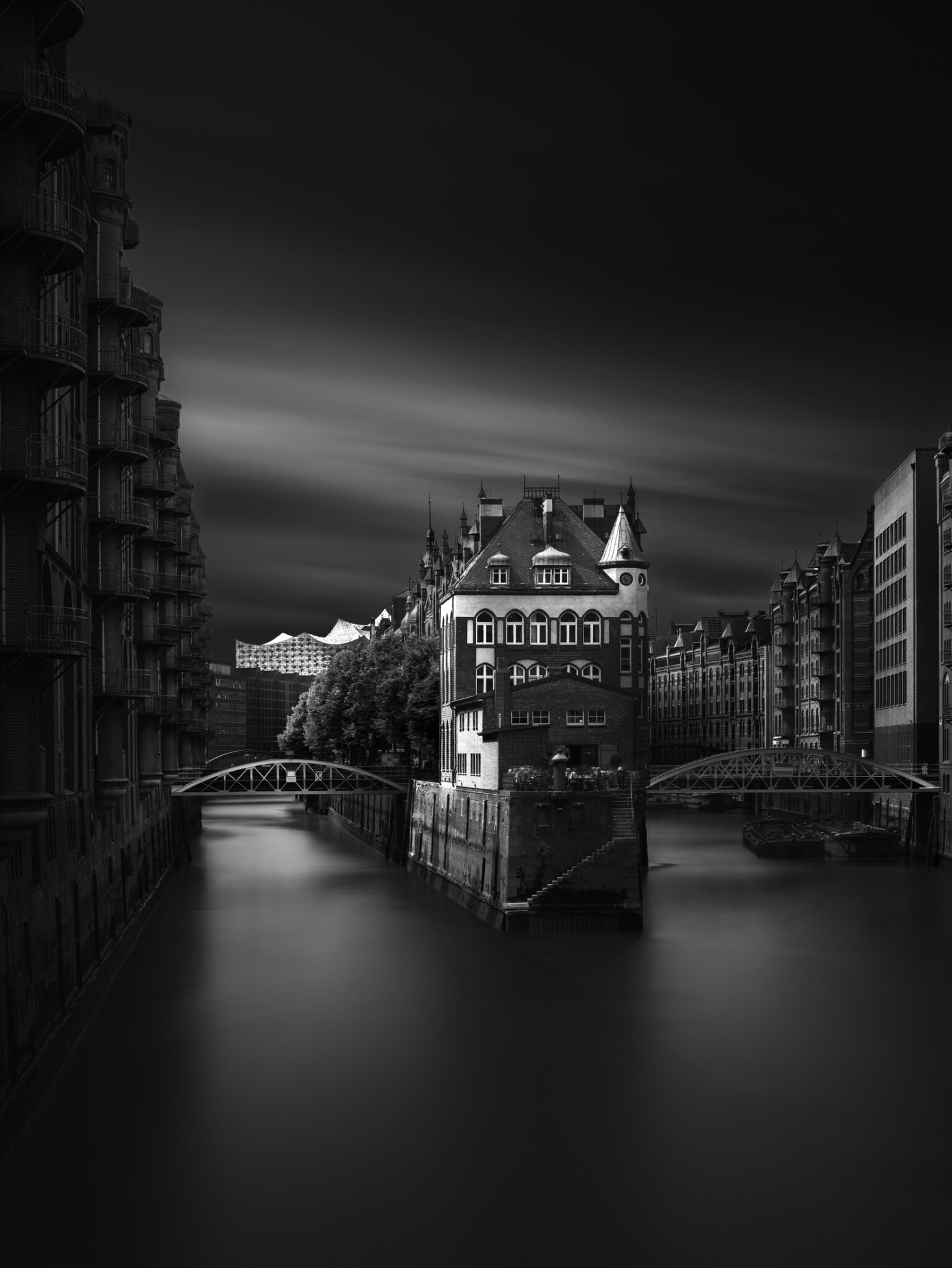 Long exposure black and white fine art photograph of Hamburg's historic Speicherstadt warehouse district reflected in a night canal