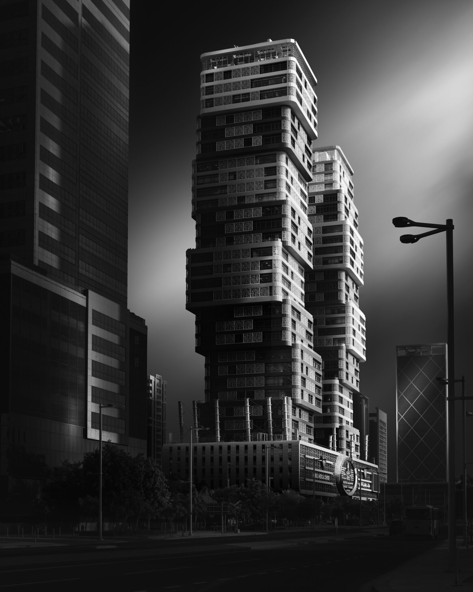 Black and white fine art photograph of dramatically stacked contemporary residential towers in a dense urban setting