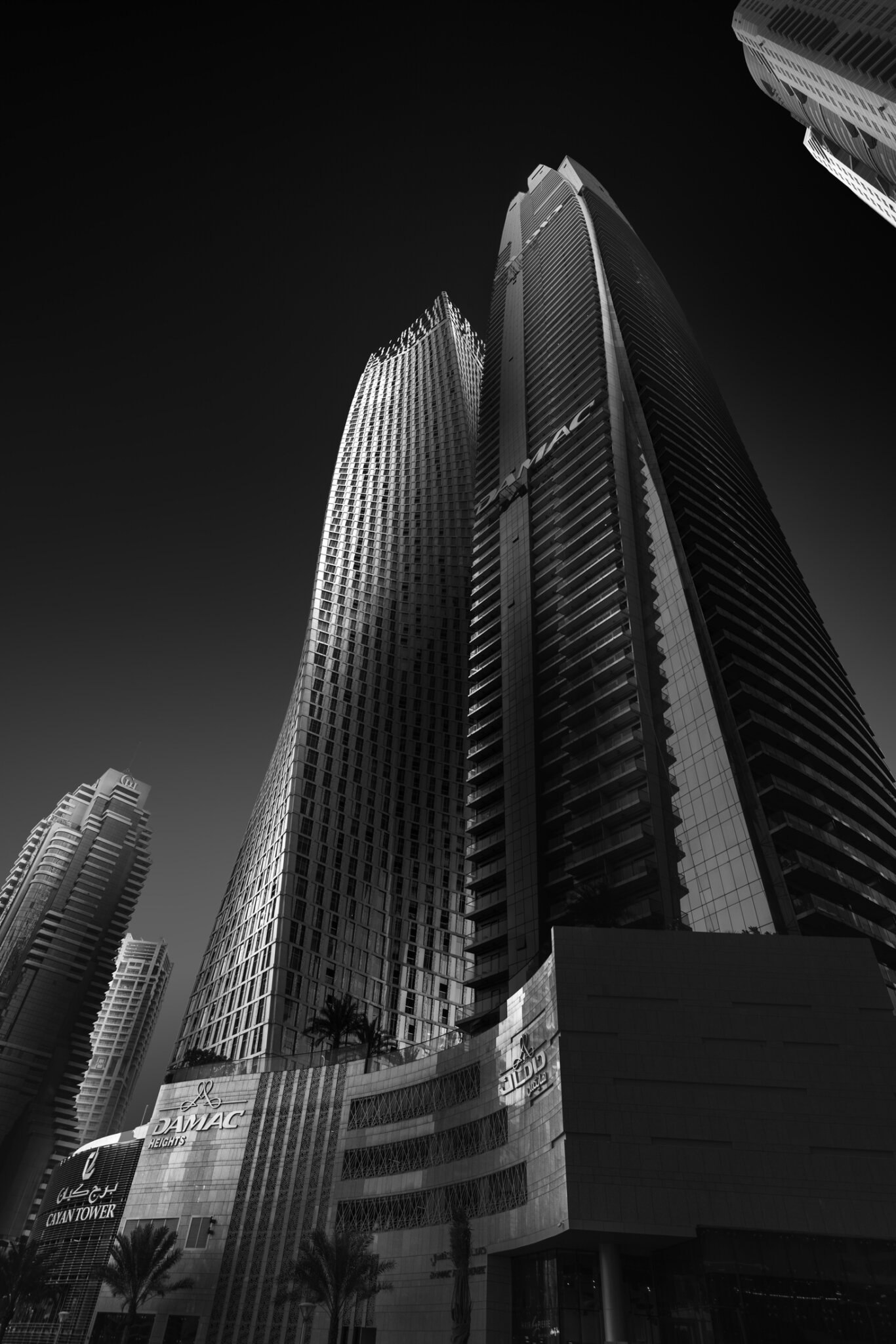 Extreme low-angle black and white fine art photograph of twin glass skyscrapers converging dramatically against a dark sky